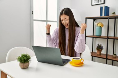 Genç Çinli kız dizüstü bilgisayarını kullanarak mutlu bir şekilde gülümsüyor..