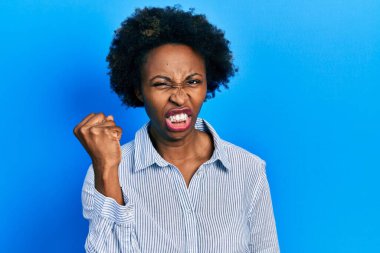 Genç afro-amerikan kadın rahat kıyafetler giyiyor kızgın ve kızgın yumruk kaldırıyor öfkeyle bağırırken. öfke ve agresif konsept. 