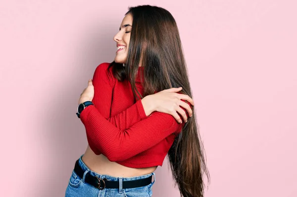 若いブルネットのティーンエイジャーは 自分自身を抱きかかえて幸せと肯定的な 自信を笑顔赤いタートルネックセーターを着ています 自己愛と自己ケア — ストック写真