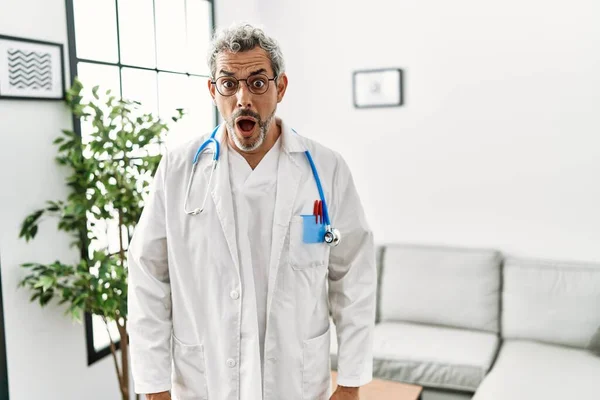 中年男人穿着医生制服和听诊器在候诊室里害怕 惊讶的表情 恐惧和兴奋的脸震惊了 — 图库照片