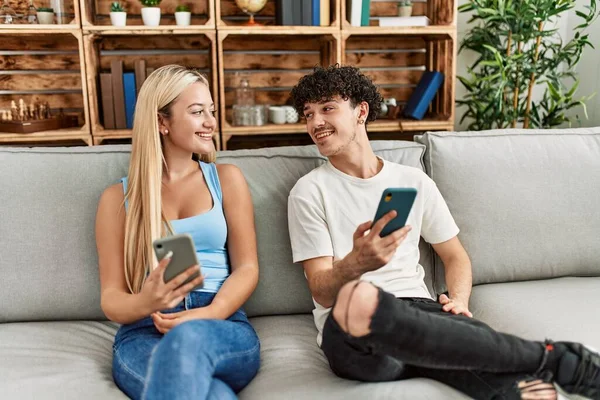 Casal Jovem Usando Smartphone Sentado Sofá Casa — Fotografia de Stock