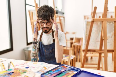 Resim stüdyosunda sakallı, başı ağrıyan bir İspanyol. Stres yüzünden. migren ağrısı. 