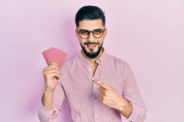 Poker kartları tutan yakışıklı adam mutlu bir şekilde elini ve parmağını gösterdi. 