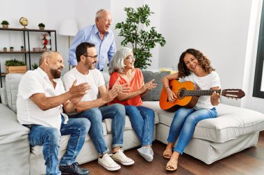 Bir grup orta yaşlı arkadaş evdeki kanepede oturup klasik gitar çalıyorlar..