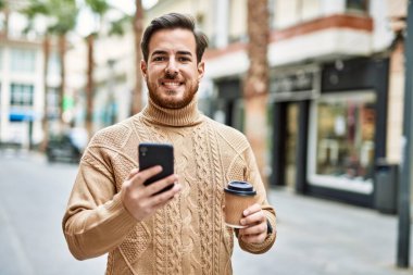 Kafkasyalı genç adam akıllı telefon kullanıyor. Şehirde kahve içiyor..