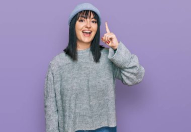 Tatlı yün şapkalı genç İspanyol kadın başarılı bir fikri işaret ediyor. Heyecanlı ve mutlu. Bir numara.. 