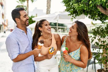 Üç İspanyol arkadaş gülerek şehirde dondurma yiyor..