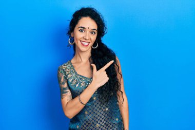 Bindi ve geleneksel kurta elbiseler giyen genç bir kadın. Yüzünde mutlu ve doğal bir ifade olan, elleri ve parmaklarıyla gülümseyen neşeli bir yüz. 