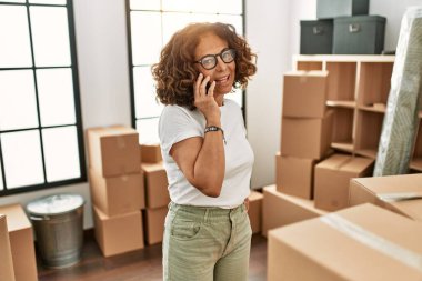 Orta yaşlı İspanyol kadın gülümsüyor. Yeni evindeki akıllı telefondan konuşuyor.