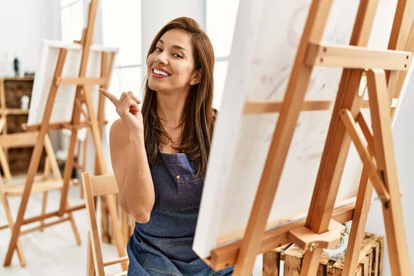 若いですラテンアーティスト女性絵画でアートスタジオ笑顔幸せなポインティングとともに手と指で側面 — ストック写真