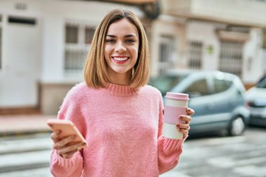 Beyaz kız akıllı telefon kullanıyor ve şehirde kahve içiyor..