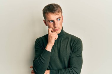 Kafkasyalı genç bir adam günlük kıyafetler giyiyordu. Kuşkuya yoğunlaşmıştı. Parmakları çenesinde ve yukarı bakıyordu. 