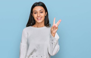 Gündelik kıyafetler giyen genç İspanyol kız üç numarayı gösterip işaret ederken kendinden emin ve mutlu bir şekilde gülümsüyor.. 