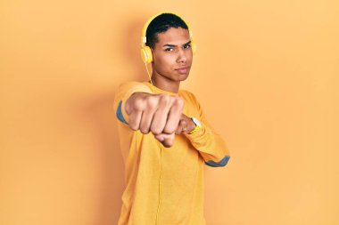 Genç Afro-Amerikalı adam müzik dinliyor kulaklıkla yumruk yumruğa dövüşüyor, agresif ve öfkeli saldırı, tehdit ve şiddet uyguluyor. 