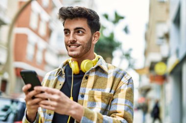 Yakışıklı İspanyol adam mutlu ve kendine güvenen akıllı telefon kullanıyor.