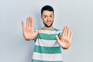 Günlük kıyafetler giyen genç İspanyol bir adam. El hareketlerini, avuç içleriyle durduruyor. Öfkeli ve hayal kırıklığına uğramış bir ifade. 