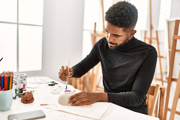 Молодой африканский художник-американец сконцентрировал живопись на керамике в художественной студии.