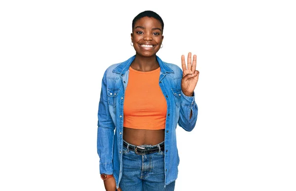 自信を持って幸せな笑みを浮かべている間 若いアフリカ系アメリカ人の女性はカジュアルな服を着て指の数3で示すと指摘 — ストック写真
