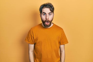 Sakallı, sıradan sarı tişörtlü beyaz bir adam şaşkınlık ve şaşkınlık dolu bir ifade, korku ve heyecan dolu bir yüz.. 