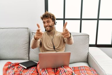 Sakallı, operatör kulaklığı takan, mutlu ve komik yüzüyle kamerayı işaret eden genç yakışıklı bir adam. iyi enerji ve titreşimler. 