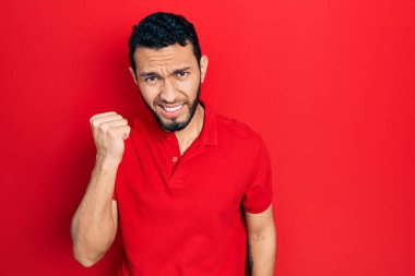 Sakallı, sıradan kırmızı tişörtlü, sinirli, kızgın yumruk kaldıran öfkeli ve öfkeyle bağıran İspanyol bir adam. öfke ve agresif konsept. 