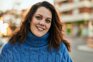 Genç İrlandalı artı cüsseli kız gülümseyerek şehirde mutlu mesut duruyor..