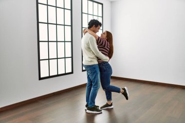 Genç İspanyol çift mutlu bir şekilde gülümsüyor ve boş yeni evlerinde birbirlerine sarılıyorlar..