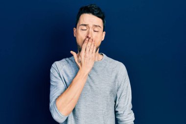 Gündelik kıyafetler giyen genç İspanyol adam ağzıyla ağzını kapatmaktan sıkılmış. Huzursuz ve uykulu.. 