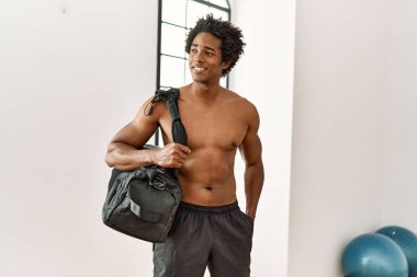 Genç Afrikalı Amerikalı gülümseyen adam spor salonunda sırt çantası taktığı için mutlu.