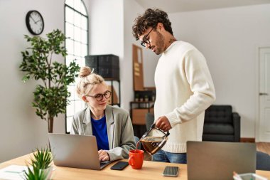 İşadamı ofisteki iş arkadaşına kahve dolduruyor.