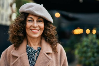 Orta yaşlı İspanyol kadın gülümseyerek şehirde mutlu mesut dikiliyor..