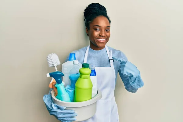 Mujer Afroamericana Con Cabello Trenzado Usando Delantal Sosteniendo Productos Limpieza —  Fotos de Stock