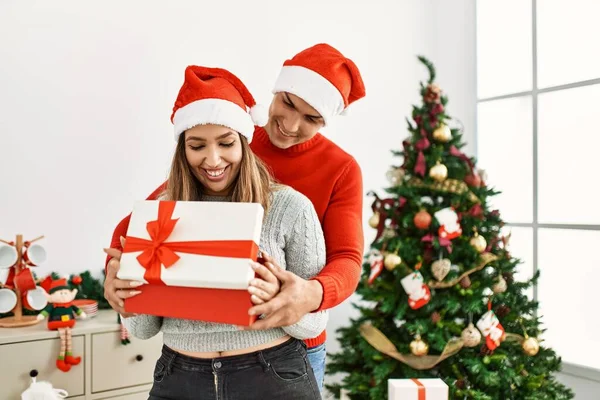 Casal Jovem Abraçando Sorrindo Feliz Usando Chapéu Natal Segurando Presente — Fotografia de Stock