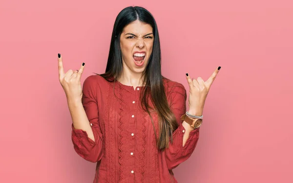 若いヒスパニック系の女性が手を上げて岩のシンボルをやって狂気の表情で叫んでカジュアルな服を着て 音楽スター 重い概念は — ストック写真