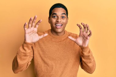 Kış süveteri giyen genç, yakışıklı İspanyol adam korku ifadesinden korkuyor ve dehşete düşüyor. El hareketlerini bırak, şok içinde bağır. panik konsepti. 