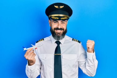 Pilot üniforması giyen İspanyol genç adam uçak oyuncağı tutuyor gururla bağırıyor, zaferi kutluyor ve kollarını kaldırarak çok heyecanlanıyor. 
