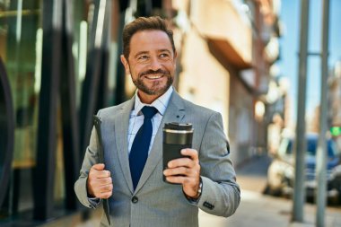 Orta yaşlı işadamı gülümseyerek şehirde kahve içiyor..