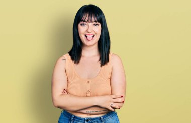 Genç İspanyol artı kolları çapraz jestli bir kadın komik bir ifadeyle mutlu bir şekilde dilini dışarı çıkarıyor.. 