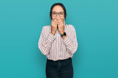 Günlük kıyafetler ve gözlük takan genç İspanyol kız gülüyor ve utanıyor kıkırdıyor ağzı ellerle, dedikoduyla ve skandal konseptiyle örtüyor. 