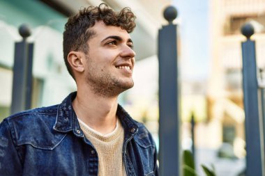 Genç İspanyol adam gülümseyerek şehirde mutlu mesut dikiliyor.