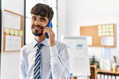 Genç İspanyol işadamı ofiste çalışan akıllı telefondan konuşuyor..