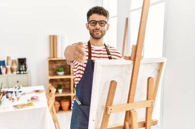 Sanat stüdyosundaki Arap genç adam dostça bir selamlama ve hoş geldin hediyesi olarak tokalaşıyor. başarılı iş. 