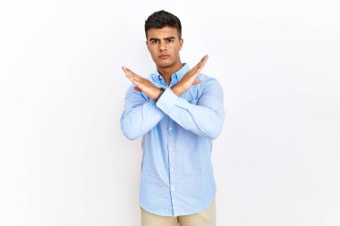 Genç İspanyol bir adam iş gömleği giyiyor. Arka planda duruyor. Reddedilmiş yüz ifadesi. 