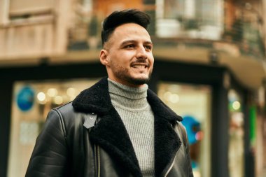 Genç Arap adam gülümsüyor, mutlu bir şekilde şehirde duruyor..