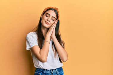 Güzel, esmer, beyaz tişört giyen, yorgun uyuyan, hayal kuran ve elleri birarada poz veren, kapalı gözlerle gülümseyen bir kadın.. 