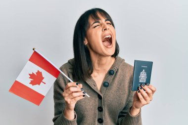 Elinde Kanada bayrağı ve pasaportu olan genç İspanyol bir kadın öfkeli ve öfkeli çığlıklar atıyor öfkeyle bağırıyor. öfke ve agresif konsept. 