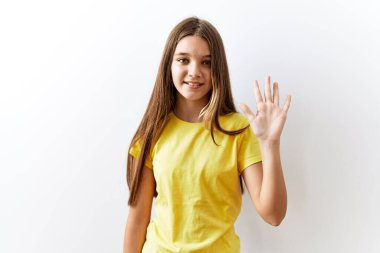 Genç esmer kız izole edilmiş arka planda yan yana duruyor. Beş numarayı işaret ediyor ve gülümsüyor. Kendinden emin ve mutlu.. 