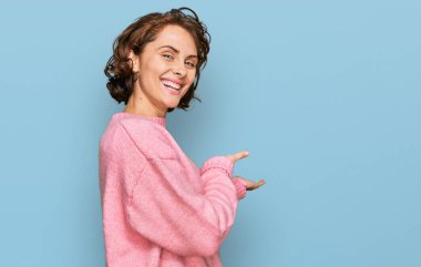 Gündelik kıyafetler giyen genç İspanyol kadın gülümseyerek doğal bir şekilde içeri girmeye davet ediyor. 