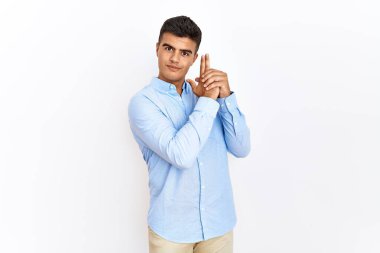 İş gömleği giyen genç İspanyol bir adam izole edilmiş arka planda duruyor. Elinde sembolik bir silahla el kol hareketi yapıyor, cinayet silahlarıyla oynuyor, öfkeli bir yüz ifadesi takınıyor. 