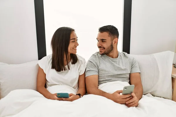 Unga Latinska Par Med Smartphone Liggande Sängen Hemma — Stockfoto